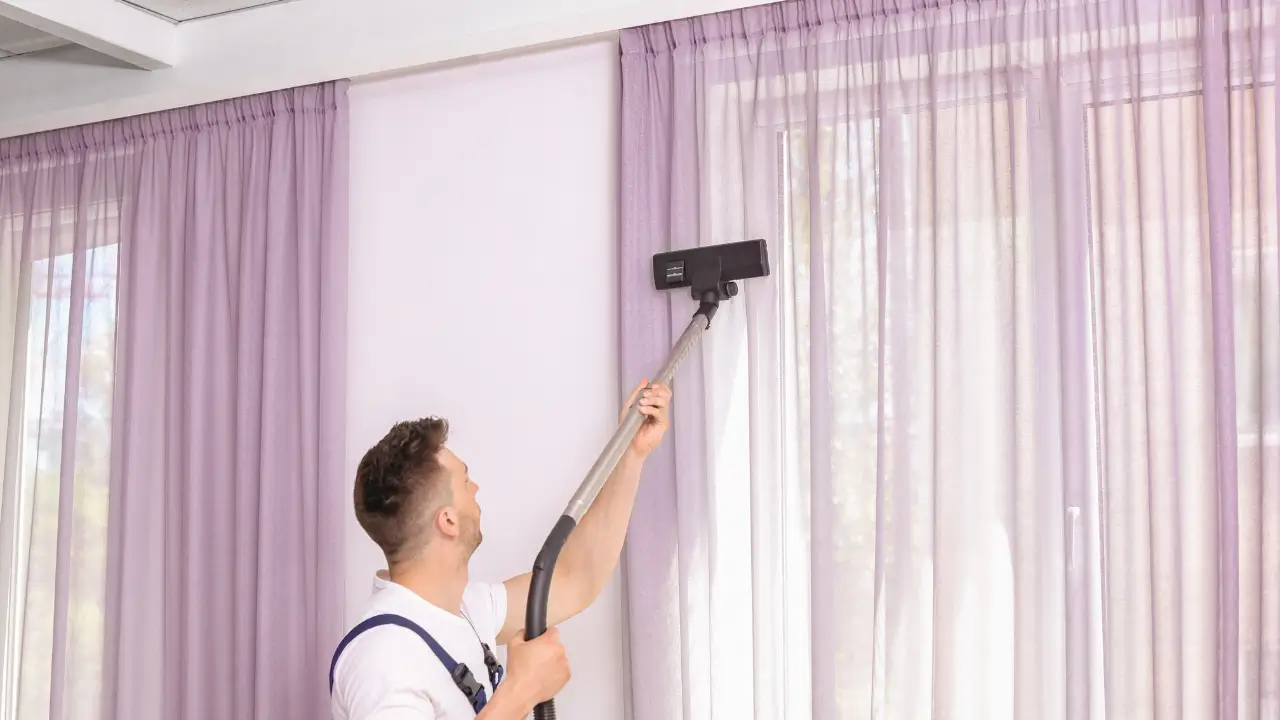Cleaner using a vacuum attachment for a curtain cleaning service.